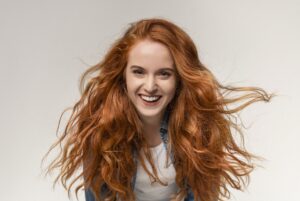 Beautiful teen girl with long ginger hair laughing at camera