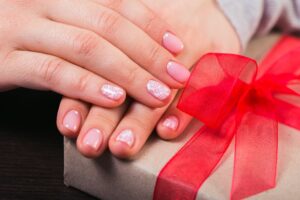 Girl holding a gift box. Manicure gel nail
